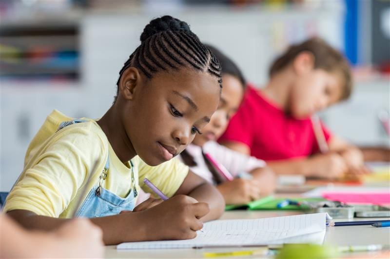 Girl writing in notebook at school.